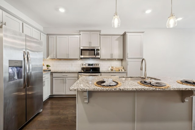 kitchen with tasteful backsplash, hanging light fixtures, appliances with stainless steel finishes, and a sink