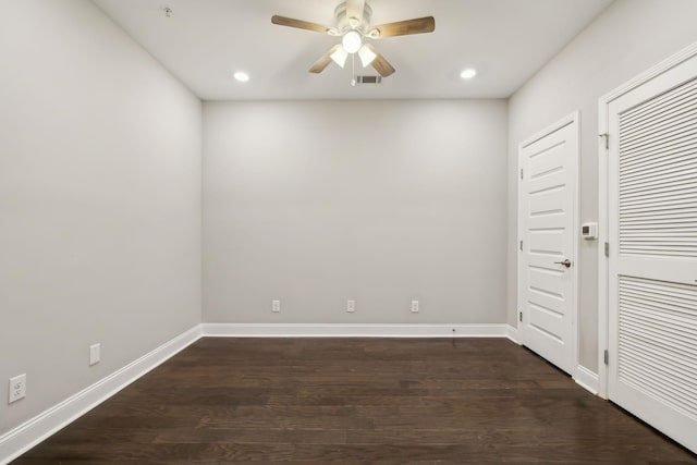 empty room with dark wood finished floors, visible vents, baseboards, and a ceiling fan