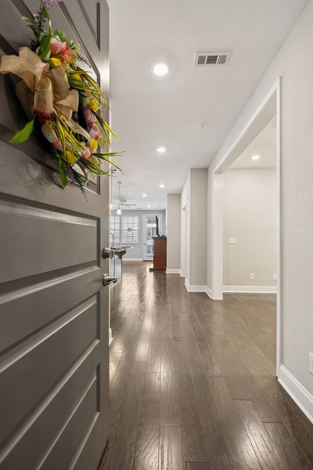 hallway featuring dark wood finished floors, visible vents, and recessed lighting