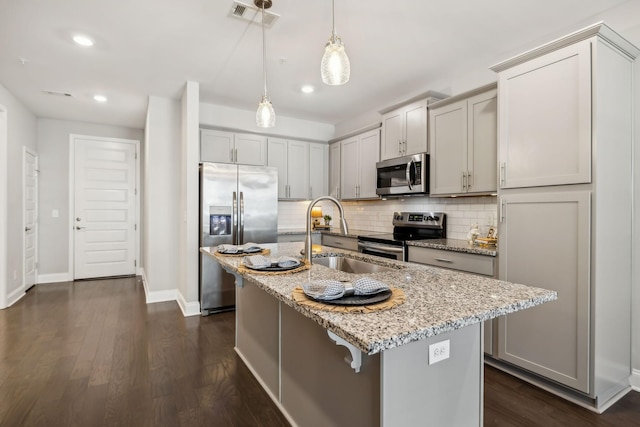 kitchen with light stone countertops, visible vents, a sink, appliances with stainless steel finishes, and backsplash