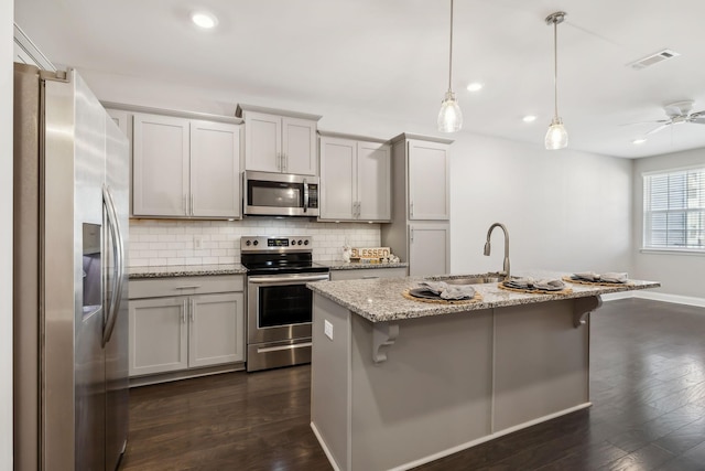 kitchen featuring visible vents, a sink, dark wood-type flooring, appliances with stainless steel finishes, and backsplash