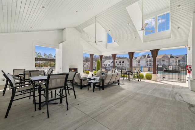 view of patio featuring a residential view, an outdoor living space with a fireplace, outdoor dining space, and fence