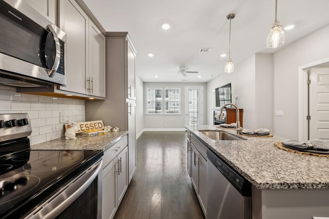 kitchen featuring visible vents, gray cabinets, a sink, tasteful backsplash, and stainless steel appliances