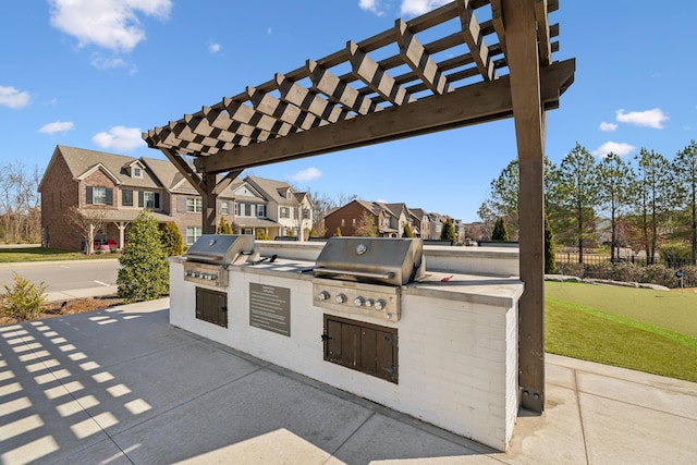 view of patio featuring exterior kitchen, a pergola, a residential view, and grilling area