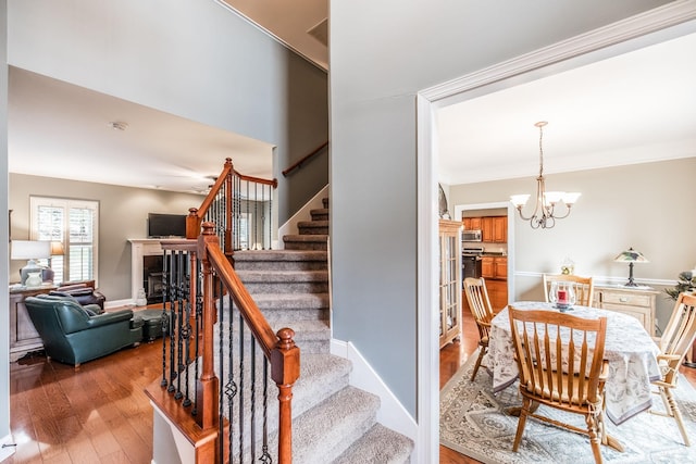1013 Five Coves Trce, Gallatin, TN 37066 - staircase with a notable chandelier, a fireplace, crown molding, and hardwood / wood-style flooring