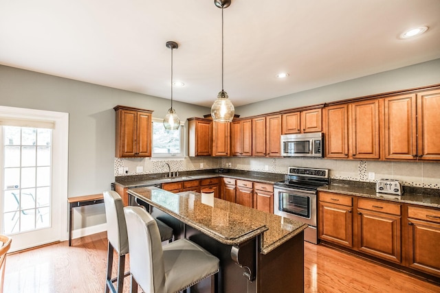1013 Five Coves Trce, Gallatin, TN 37066 - kitchen featuring backsplash, brown cabinets, light wood finished floors, and stainless steel appliances