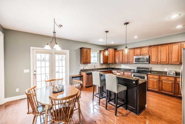 1013 Five Coves Trce, Gallatin, TN 37066 - kitchen featuring a kitchen island, a breakfast bar area, light wood-type flooring, brown cabinets, and stainless steel appliances
