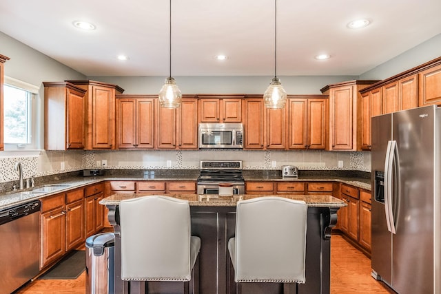 1013 Five Coves Trce, Gallatin, TN 37066 - kitchen featuring light wood finished floors, appliances with stainless steel finishes, brown cabinetry, and a sink