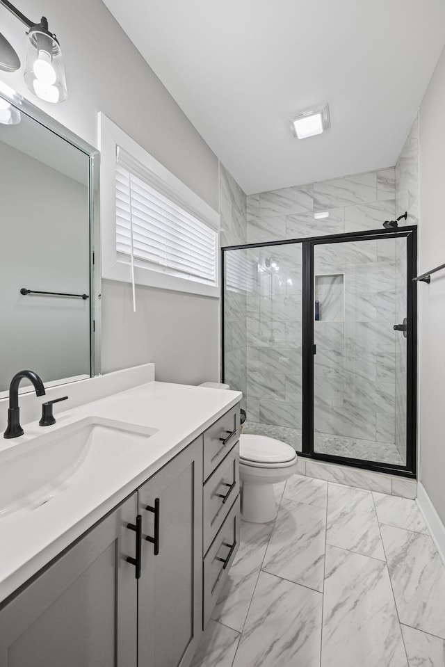 bathroom with vanity, toilet, marble finish floor, and a stall shower