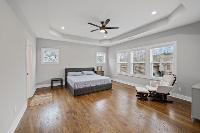 bedroom featuring recessed lighting, a raised ceiling, baseboards, and wood finished floors