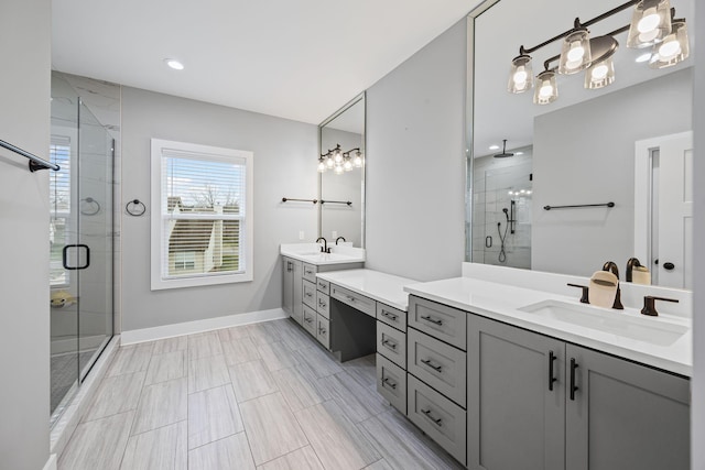 full bathroom with a stall shower, two vanities, baseboards, and a sink