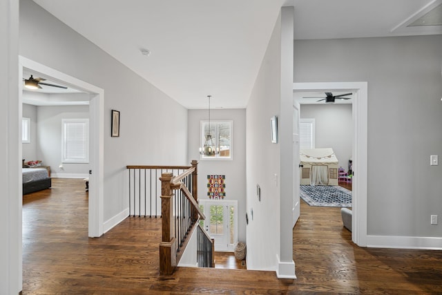 hallway with an inviting chandelier, wood finished floors, an upstairs landing, and baseboards