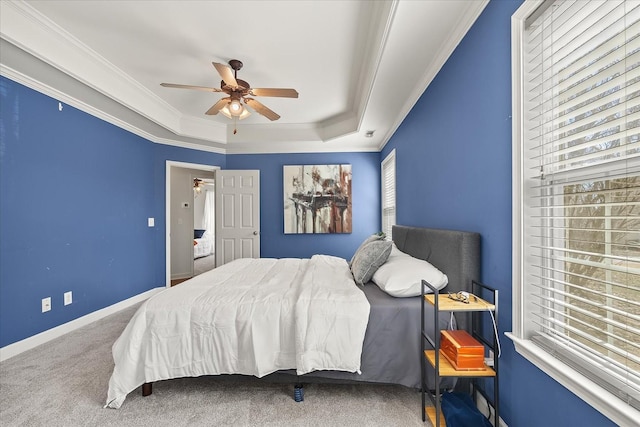 carpeted bedroom featuring ceiling fan, a tray ceiling, baseboards, and ornamental molding