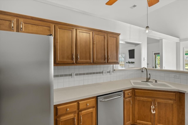 kitchen featuring brown cabinetry, a ceiling fan, a sink, appliances with stainless steel finishes, and backsplash