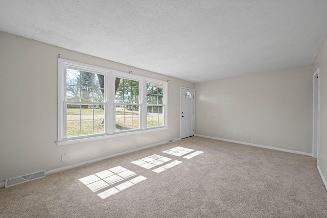 spare room with visible vents, baseboards, carpet, and a textured ceiling