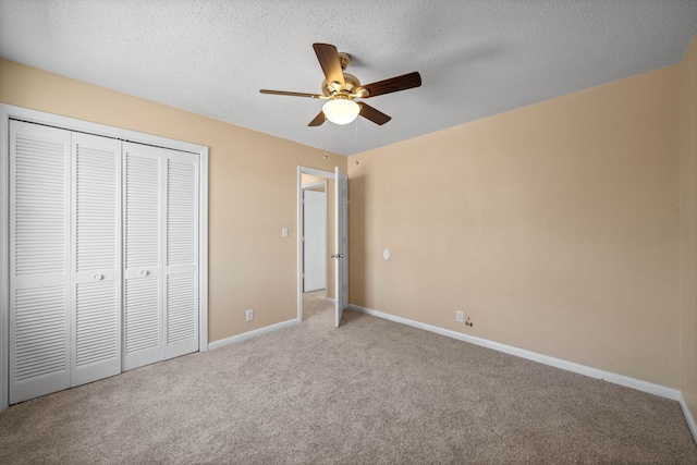 unfurnished bedroom featuring a ceiling fan, a textured ceiling, a closet, carpet floors, and baseboards