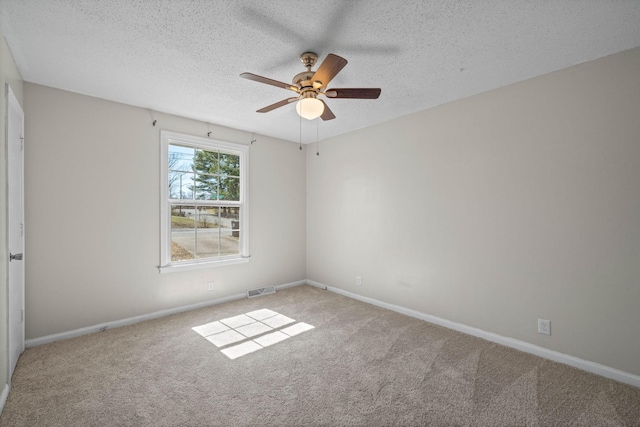 carpeted spare room featuring baseboards, visible vents, a textured ceiling, and ceiling fan