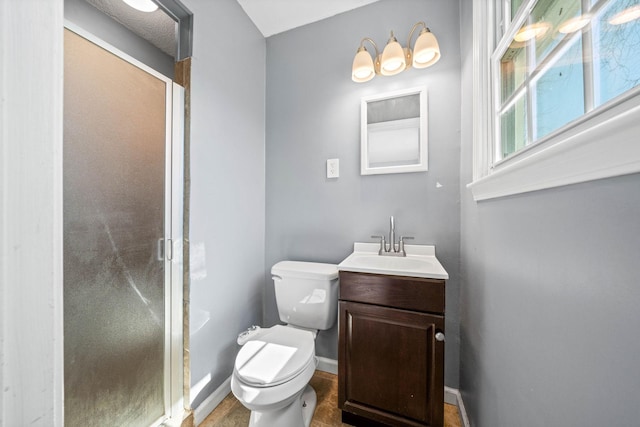 bathroom with toilet, a stall shower, vanity, and baseboards