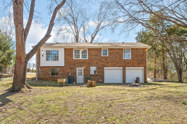 back of house with brick siding, central AC unit, a yard, and a garage