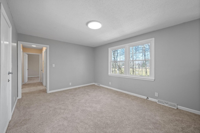 unfurnished room featuring visible vents, baseboards, light colored carpet, and a textured ceiling