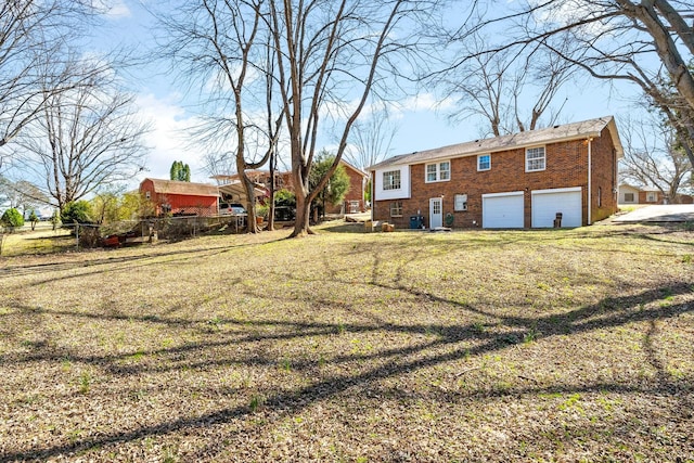 back of house featuring fence, a garage, a lawn, and brick siding