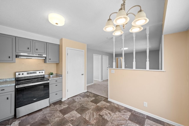 kitchen featuring baseboards, under cabinet range hood, light countertops, gray cabinets, and electric stove