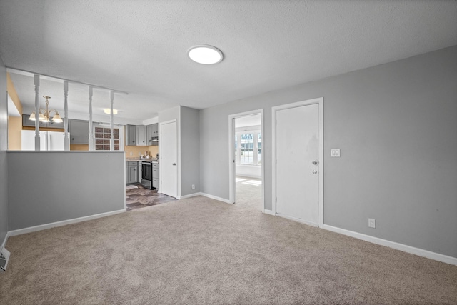 unfurnished living room with a textured ceiling, baseboards, dark colored carpet, and a chandelier