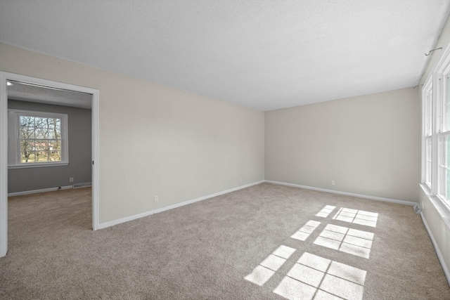 carpeted empty room featuring baseboards and a textured ceiling