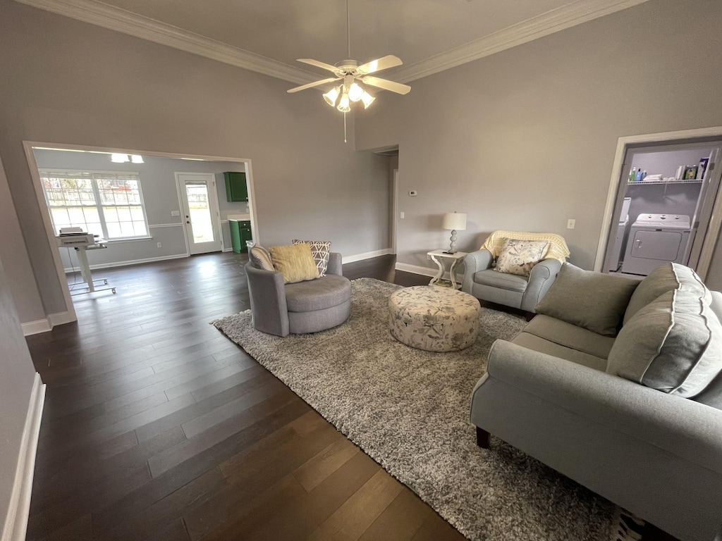 living area featuring washer / clothes dryer, crown molding, baseboards, and dark wood-style flooring