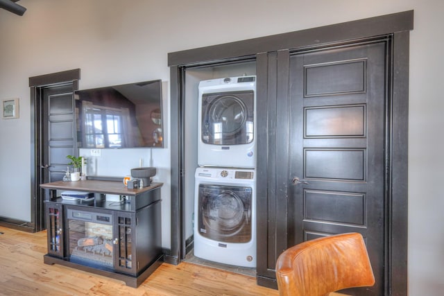 laundry room featuring laundry area, light wood-style flooring, baseboards, and stacked washer / drying machine