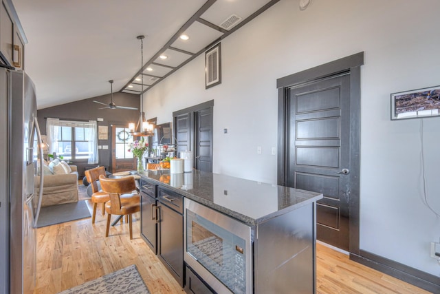 kitchen with visible vents, open floor plan, dark stone counters, light wood-style floors, and stainless steel fridge with ice dispenser