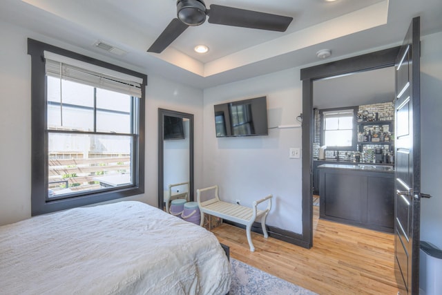 bedroom with recessed lighting, visible vents, a raised ceiling, and light wood finished floors