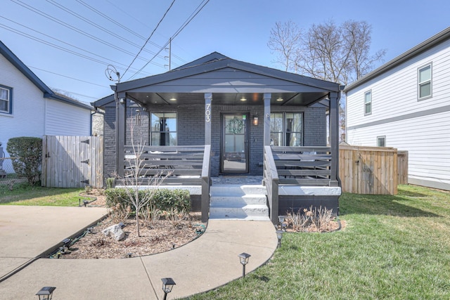 view of front of home featuring brick siding, fence, a porch, a front yard, and a gate