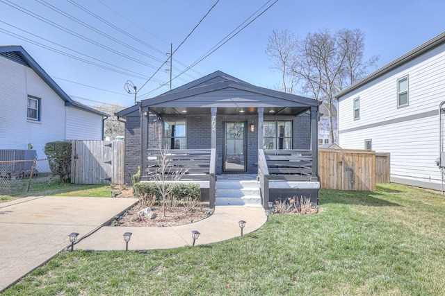 view of front of house featuring brick siding, a front lawn, fence, a porch, and a gate