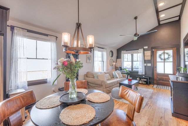 dining area featuring ceiling fan with notable chandelier, light wood-type flooring, and lofted ceiling