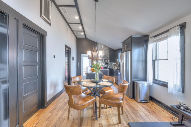 dining space featuring lofted ceiling, light wood-style flooring, plenty of natural light, and a chandelier