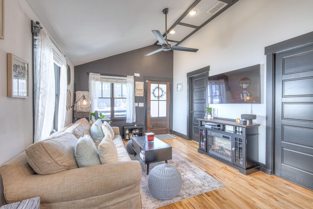 living room with visible vents, wood finished floors, ceiling fan, and vaulted ceiling