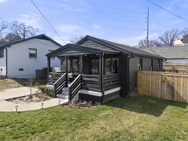 view of front of house with cooling unit, brick siding, a front yard, and fence