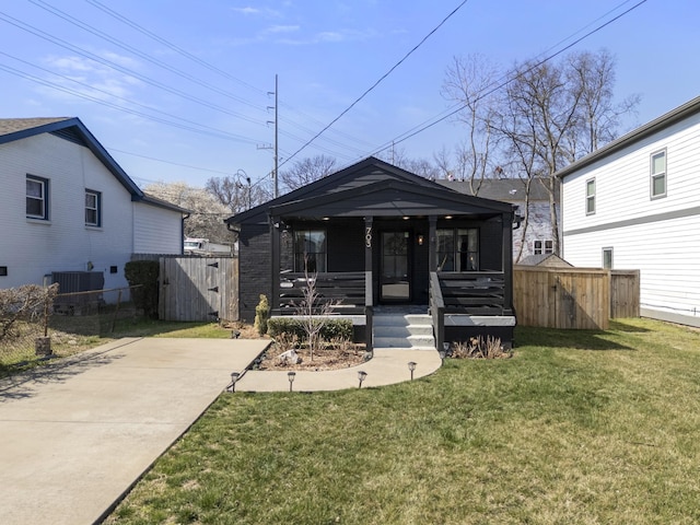 view of front facade with a front yard, fence, covered porch, and central AC