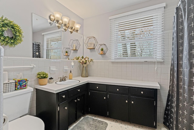 full bathroom with a wealth of natural light, toilet, tile walls, and vanity