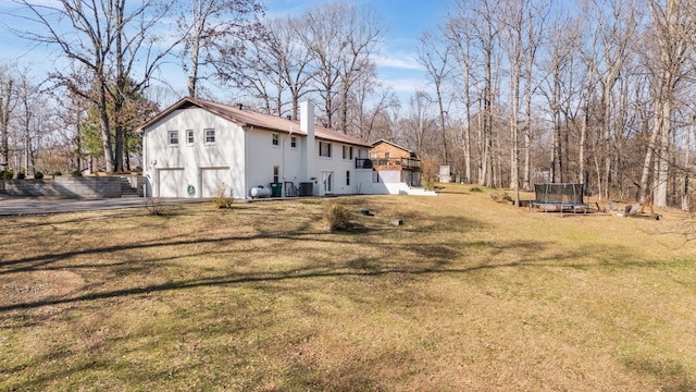 view of yard with a trampoline, driveway, and an attached garage