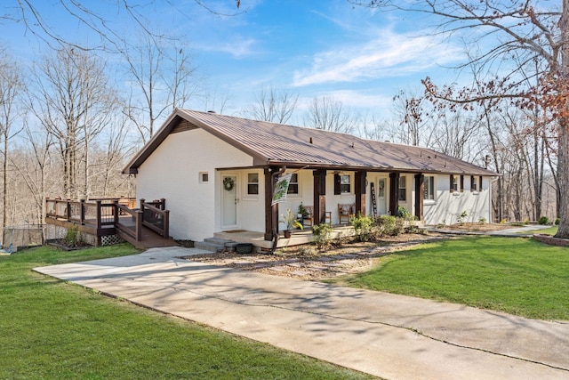 view of front of home with a standing seam roof, covered porch, metal roof, and a front yard