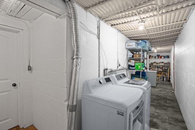 clothes washing area with washer and dryer and concrete block wall