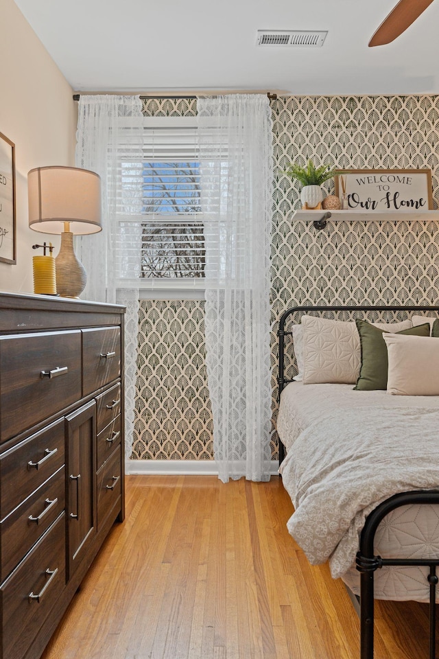 bedroom featuring visible vents, ceiling fan, and light wood-style floors