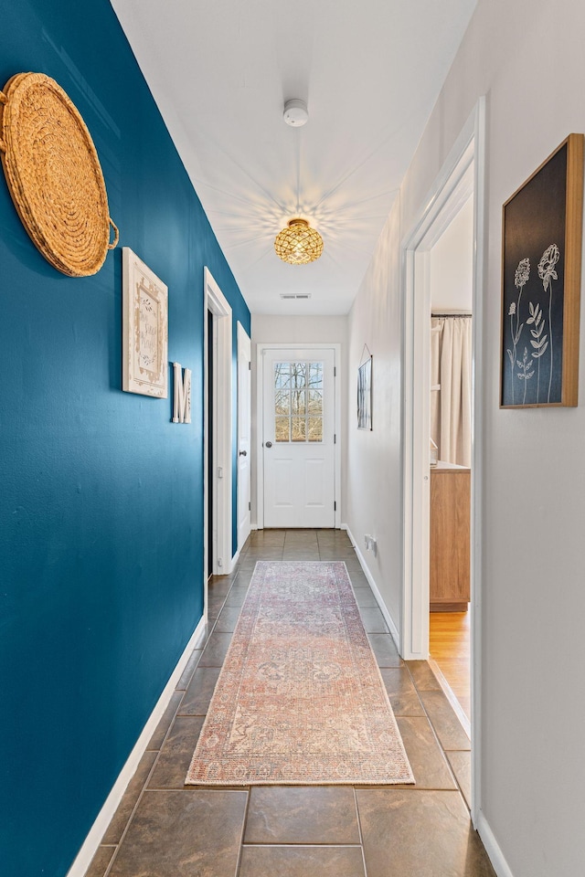 hallway featuring tile patterned flooring, baseboards, and visible vents