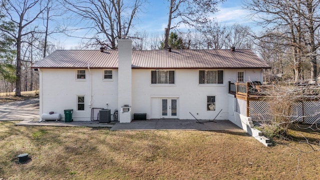 rear view of house featuring french doors, cooling unit, metal roof, a chimney, and a patio area