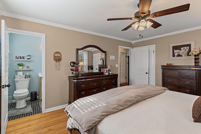 bedroom with light wood finished floors, crown molding, ceiling fan, baseboards, and ensuite bathroom