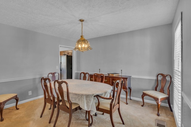 dining area with visible vents, baseboards, light carpet, a notable chandelier, and a textured ceiling