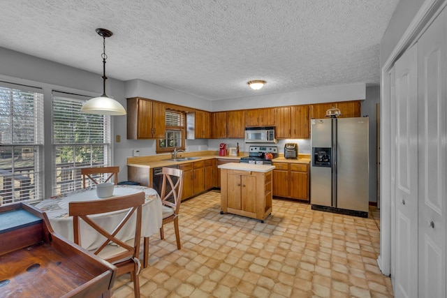 kitchen with brown cabinets, a sink, a center island, stainless steel appliances, and light countertops