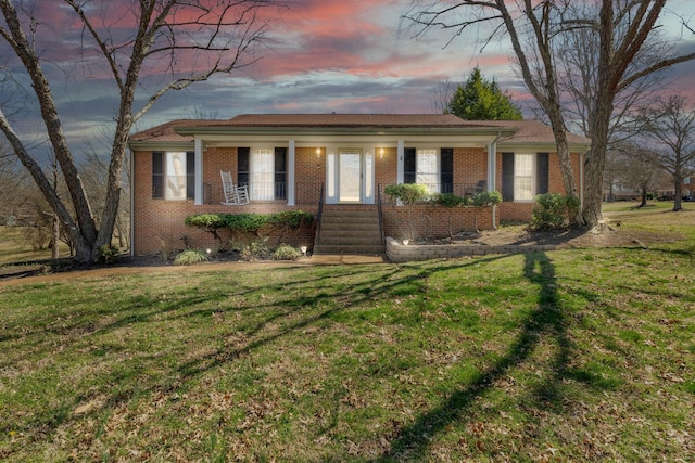 ranch-style house with a porch, brick siding, and a front yard